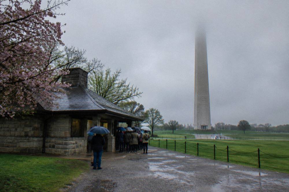 Visitors gathered at a stone ticket lodge near the Washington Monument grounds