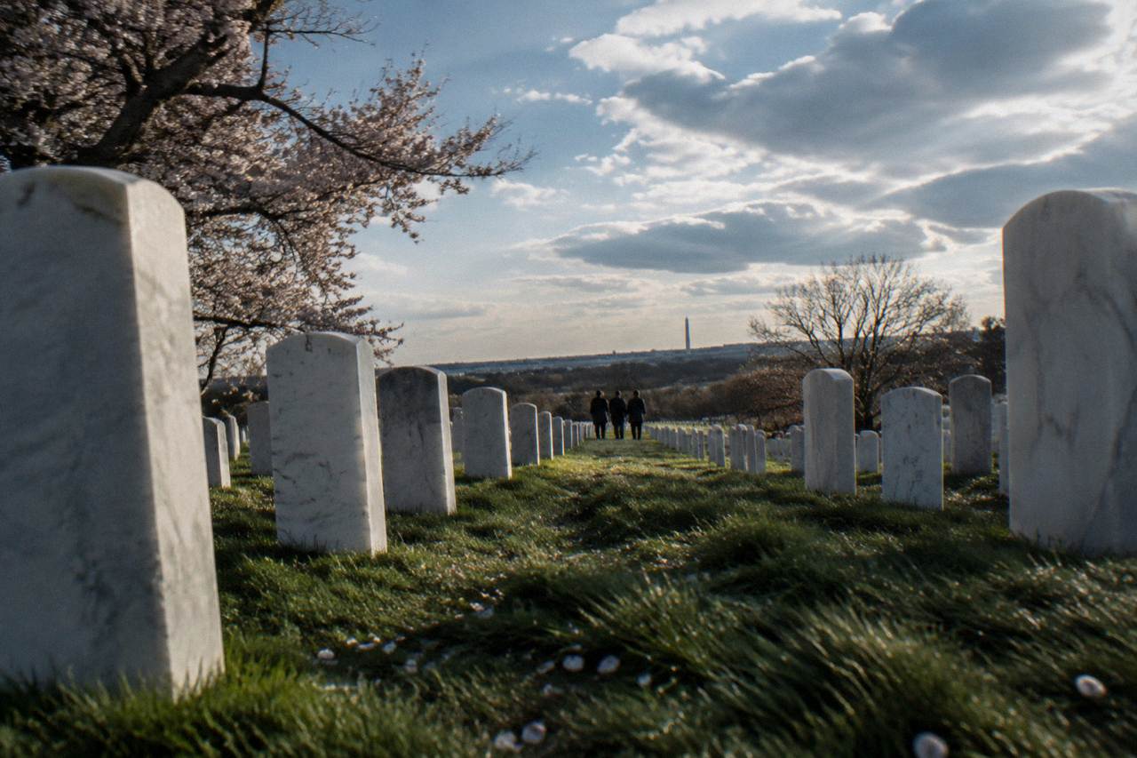 Rows of white headstones on green hills under an open sky