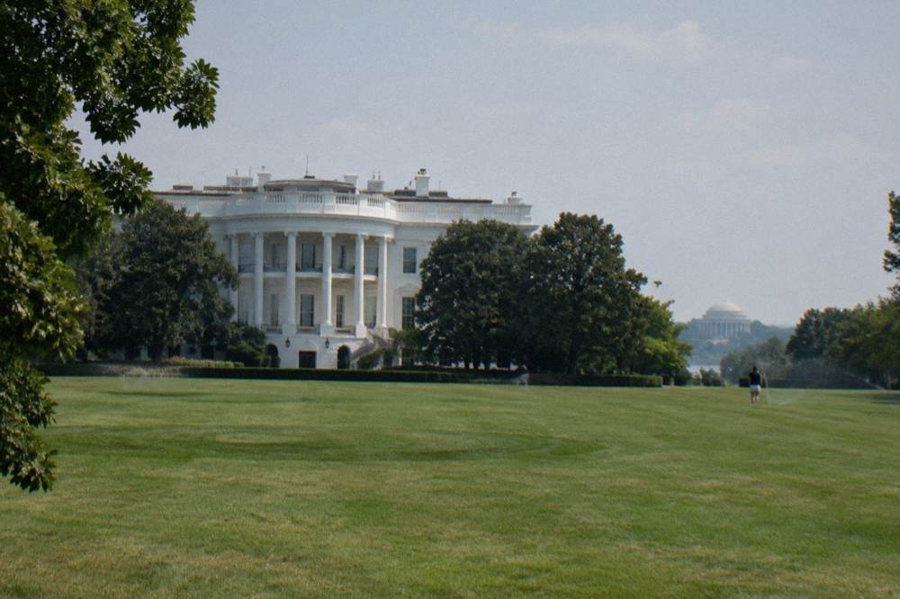 White House south facade viewed across a wide green lawn with trees at the edges