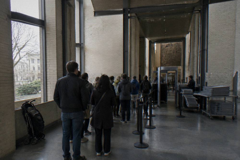 Museum entrance hall with visitors waiting at a security checkpoint