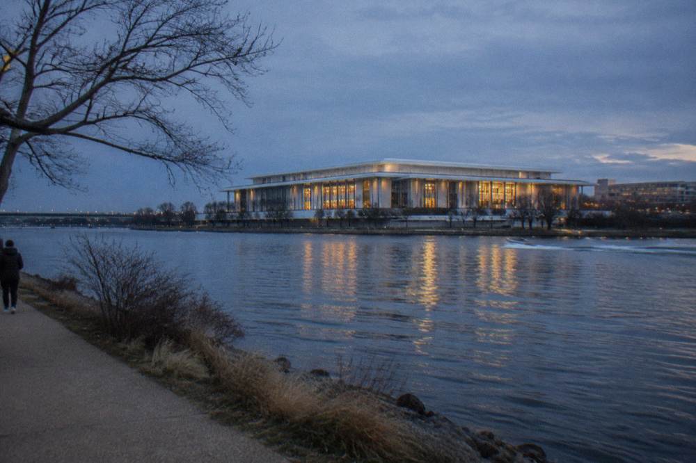 The Kennedy Center seen from across the Potomac River with the water reflecting the building at dusk