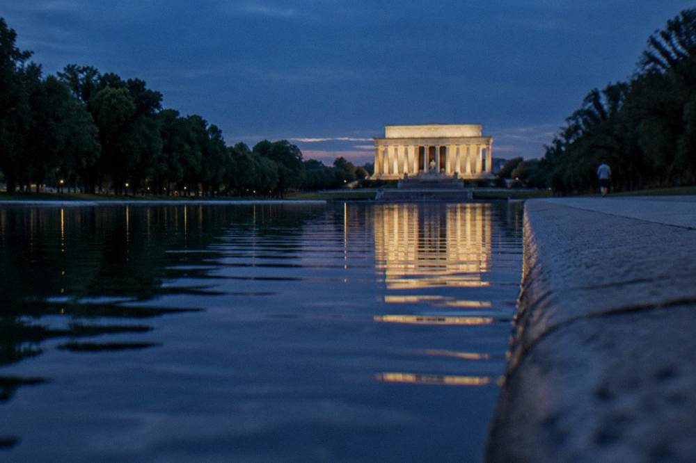 The Lincoln Memorial lit up at twilight with a reflection in the long Reflecting Pool
