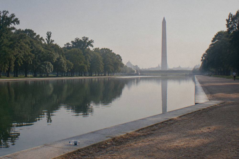 Washington Monument seen from the National Mall lawn with the reflecting pool in the foreground