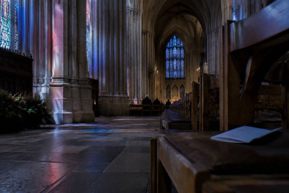 Stone arches and stained glass inside a large gothic cathedral nave