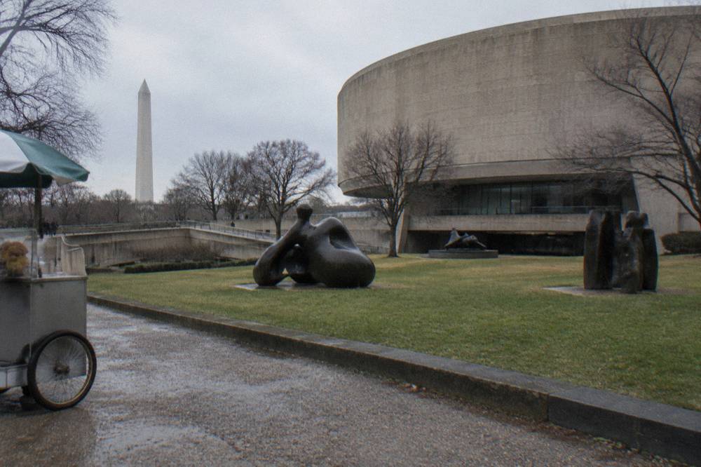 Modern art museum building with curved concrete walls beside an outdoor sculpture plaza