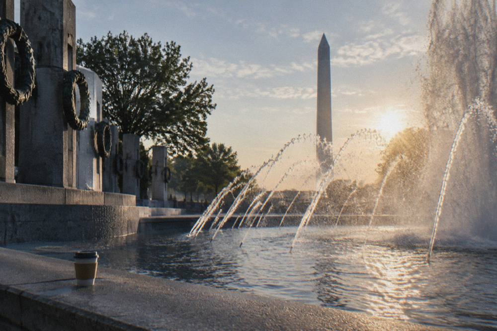 The World War II Memorial fountain with the Washington Monument behind it in morning light