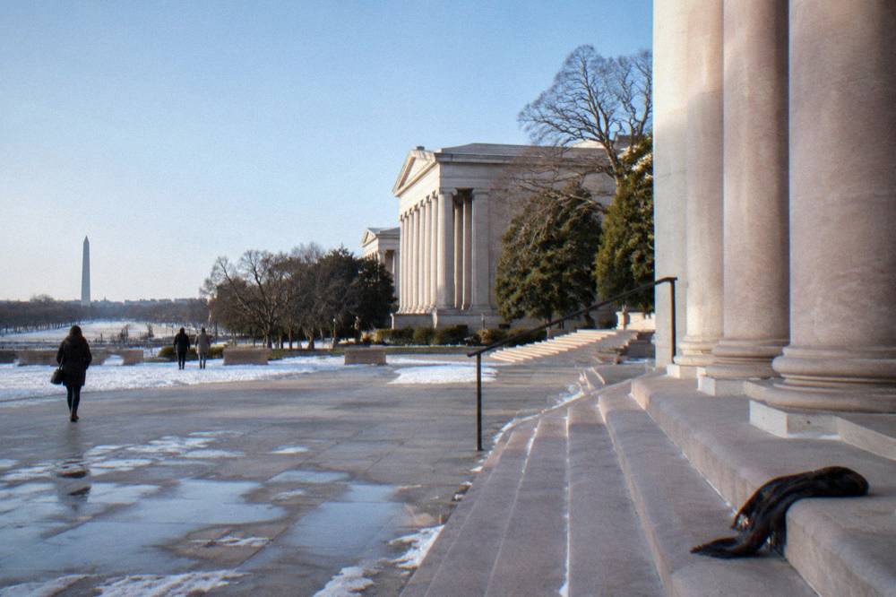 Stone museum building with columns and a wide plaza facing the National Mall lawn