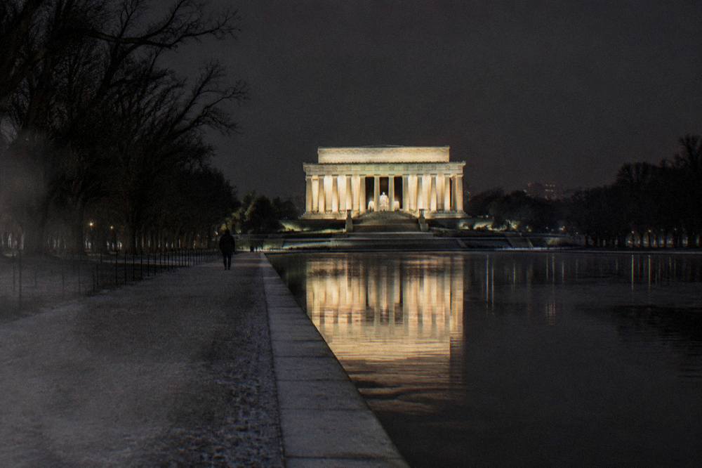 The Lincoln Memorial glowing under floodlights with the Reflecting Pool in the foreground at night