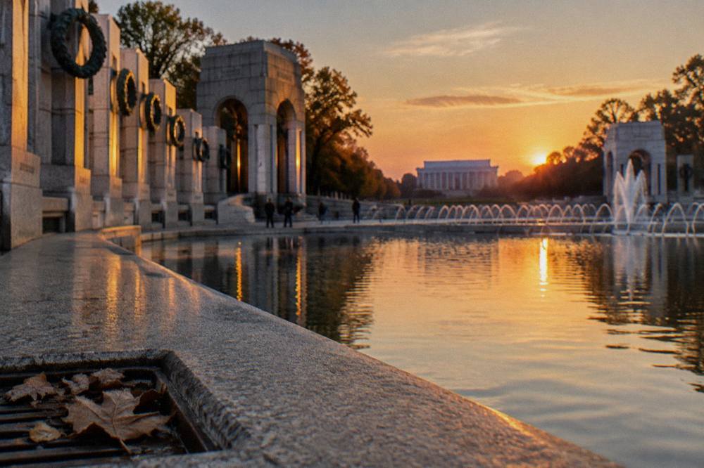 Stone memorial columns and a reflecting pool on the National Mall in late afternoon light