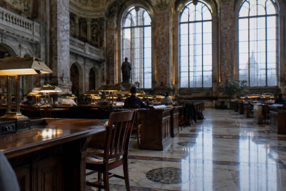 Reading room with tall arched windows and rows of desks