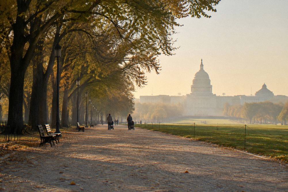 People strolling along a wide park path with the Capitol dome in the distance