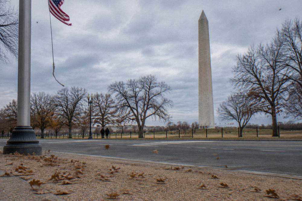 The Washington Monument rising above trees and open parkland on a clear day
