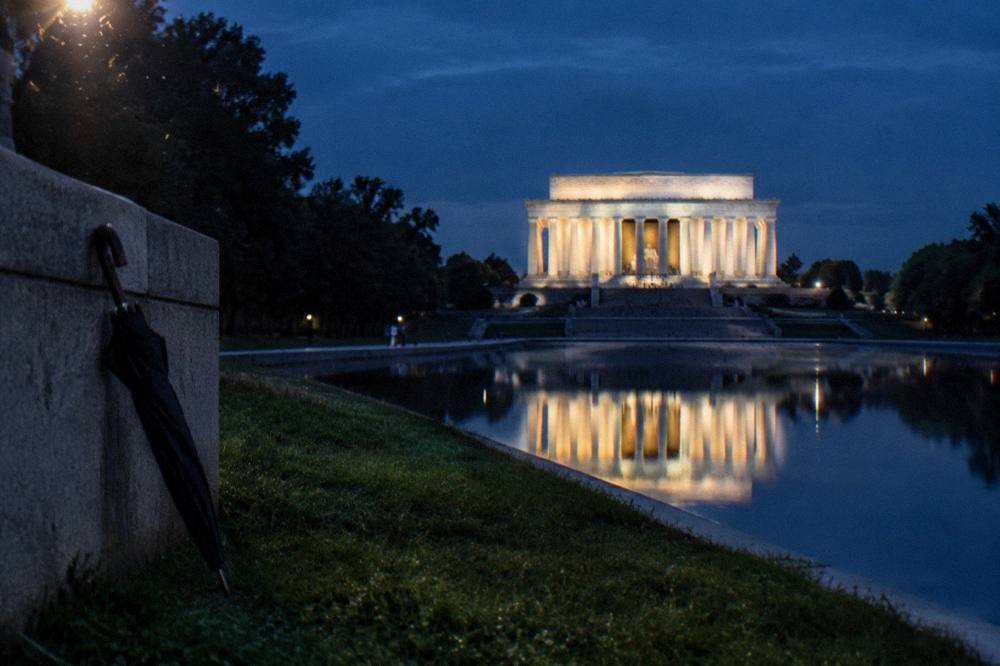 Evening view of the illuminated Lincoln Memorial columns reflected in the Reflecting Pool