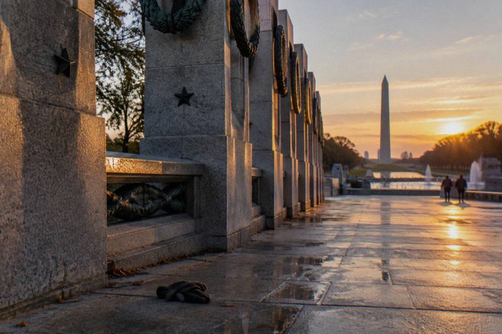 Stone memorial columns along the National Mall at golden hour with open walkways