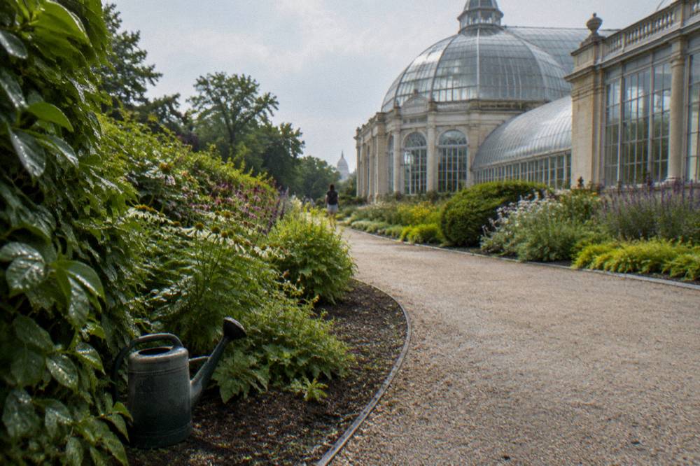 Garden pathways with seasonal blooms and a glass conservatory building