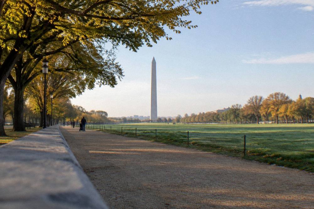 Open park pathway with the Washington Monument in the distance and people strolling