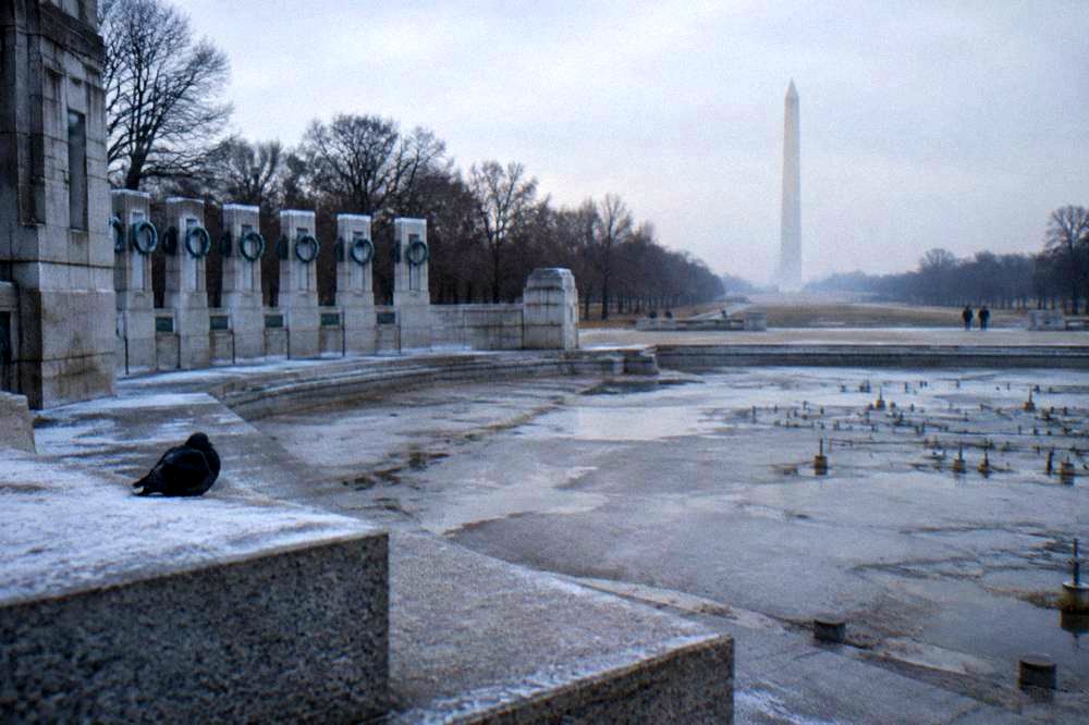 The World War II Memorial fountain and stone columns with the Washington Monument behind