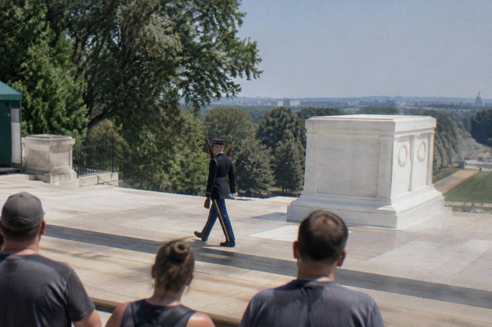 An honor guard sentry marching in front of the white marble Tomb of the Unknown Soldier