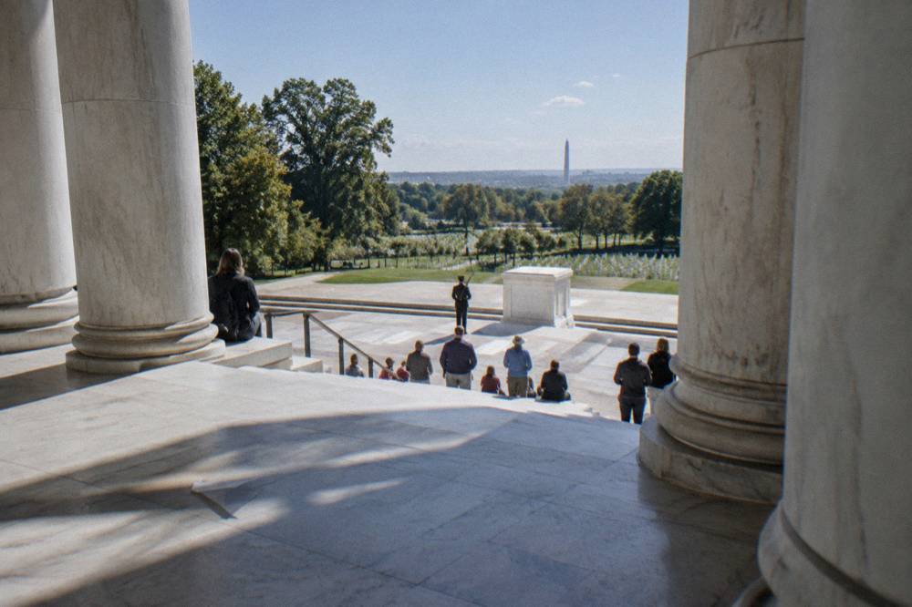 The white marble Memorial Amphitheater steps with visitors gathered for a guard ceremony