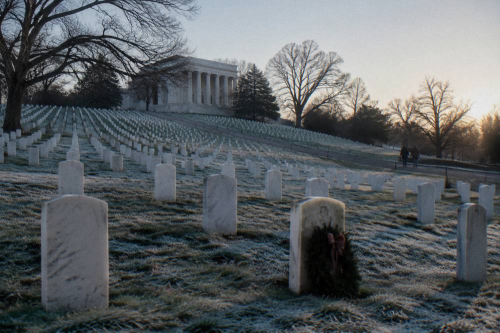 Cemetery hillside with rows of white headstones and a stone amphitheater