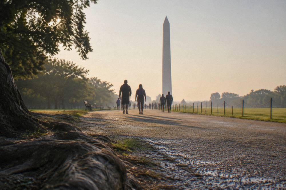 Visitors on the National Mall walking toward the Washington Monument in morning light